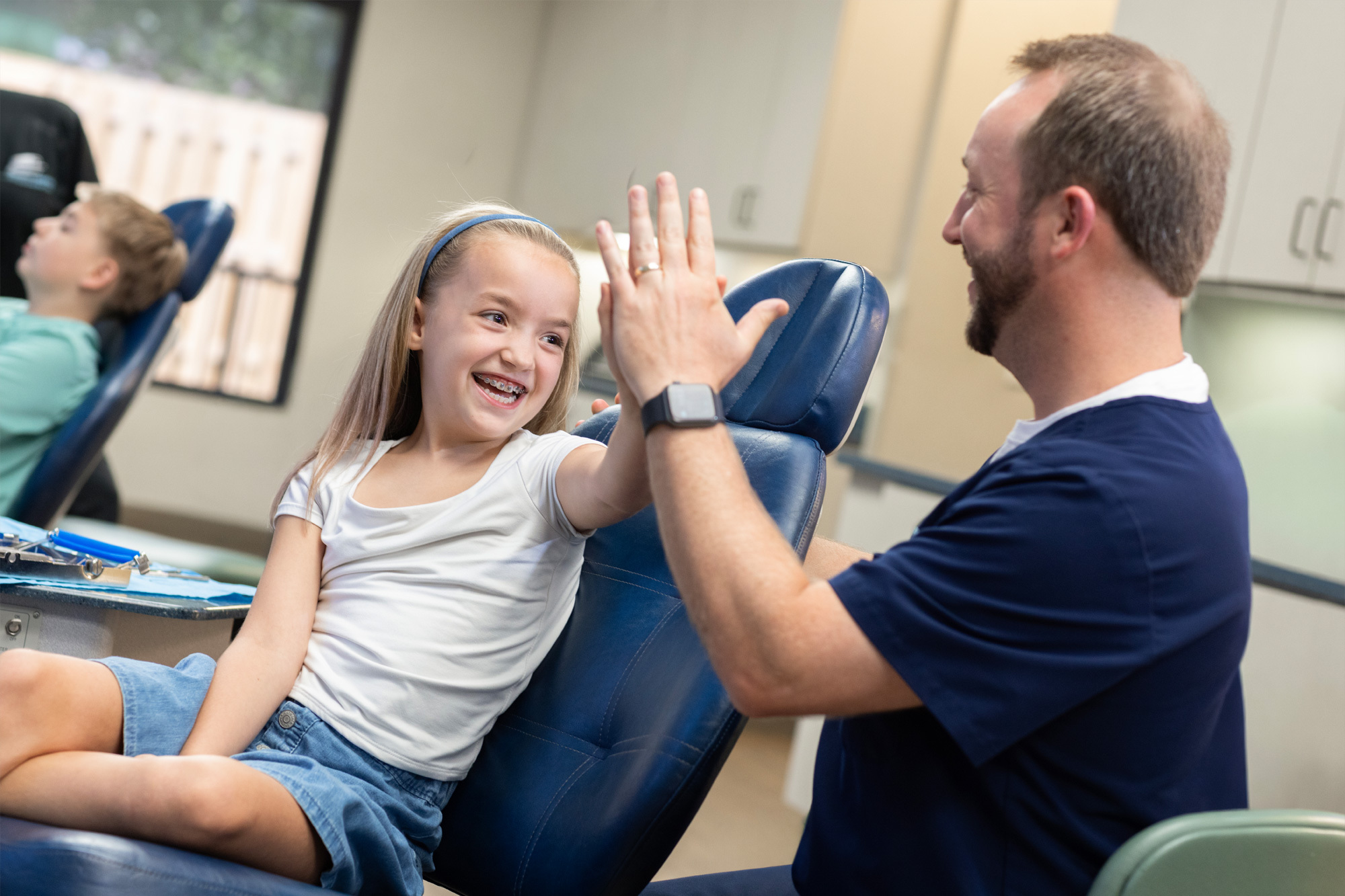 smile child patient holding clear aligners and metal braces